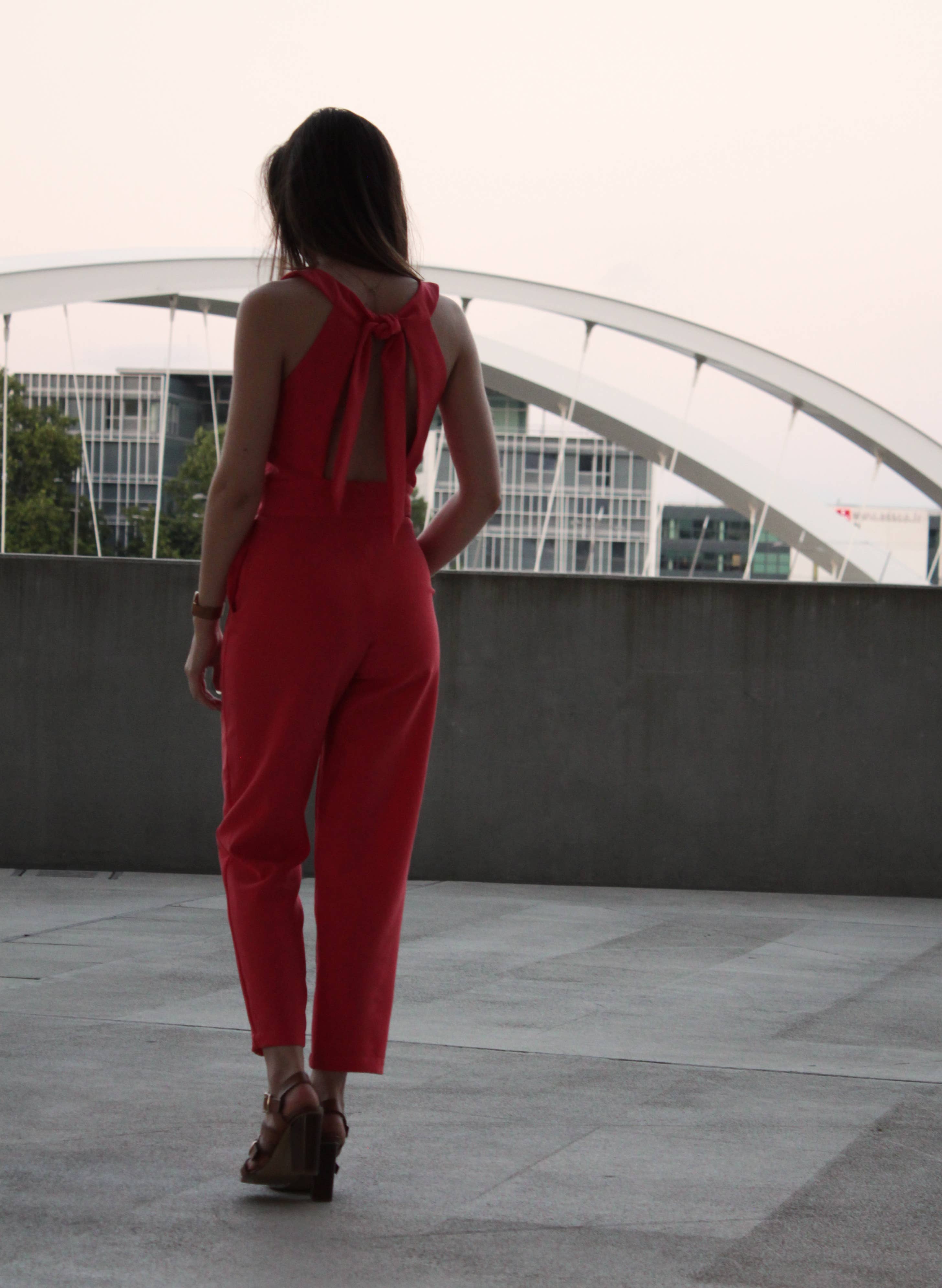 Side back view of the red Aurore Jumpsuit showing tie detail
