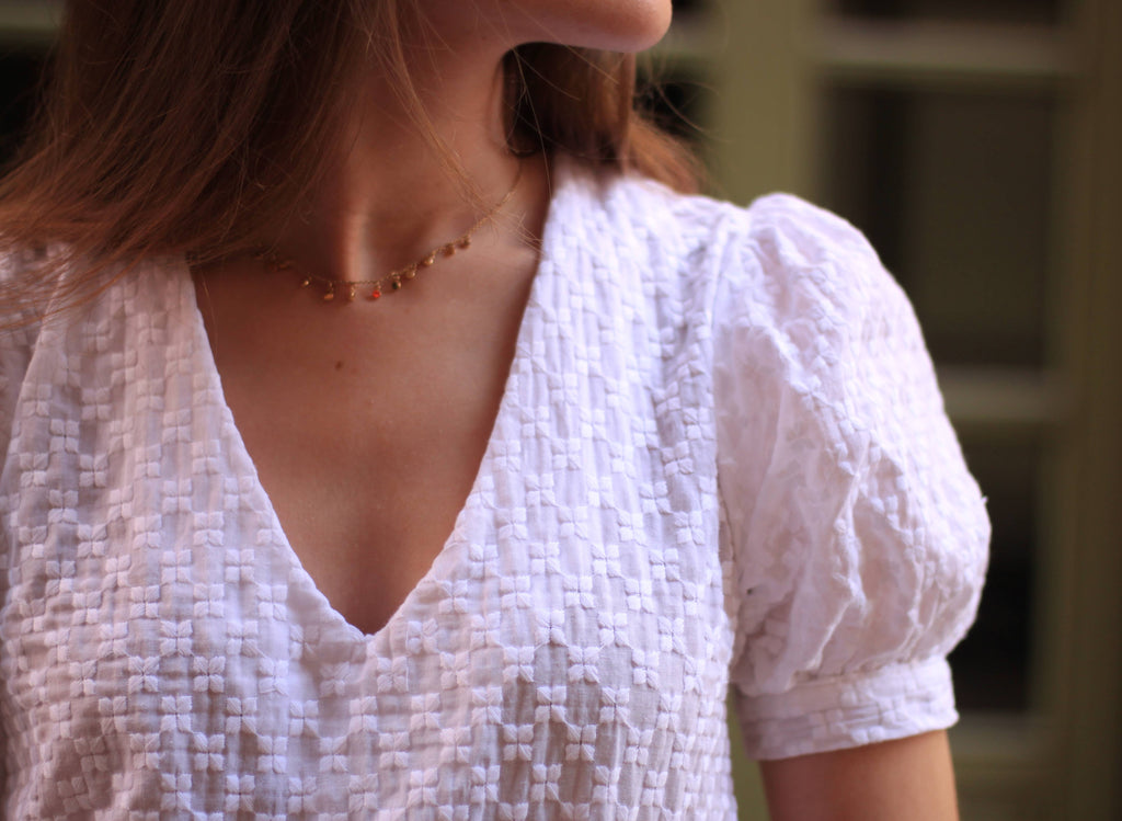 Close-up of the Eléanor Top V-neck and gathered puff sleeve in white textured fabric