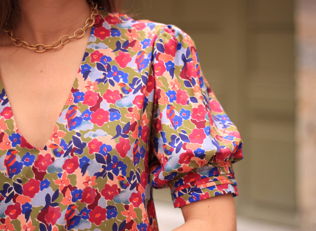 Close-up of the Calie Dress puff sleeve and V-neck in red and blue floral fabric