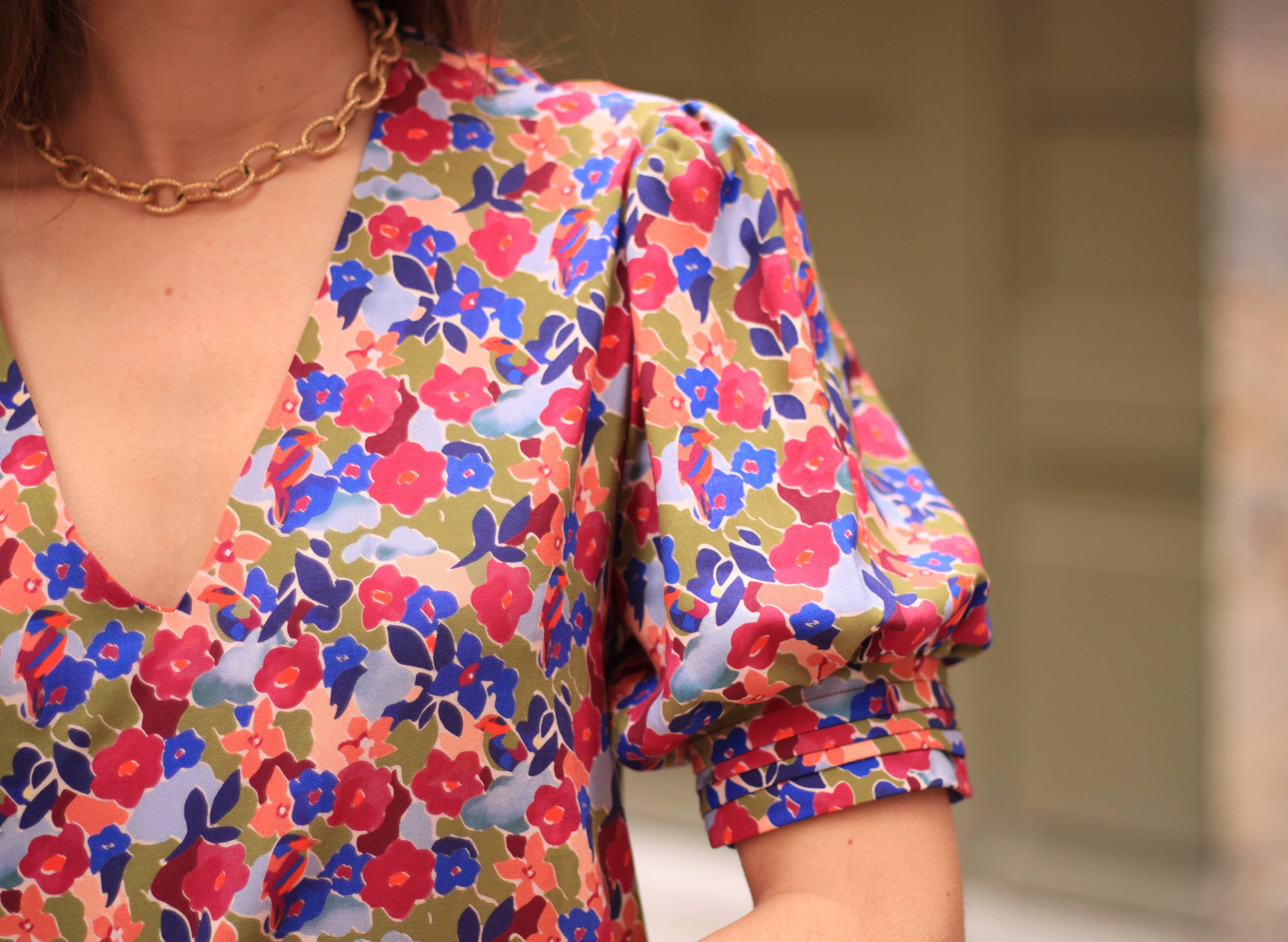 Close-up of the Calie Dress puff sleeve and V-neck in red and blue floral fabric