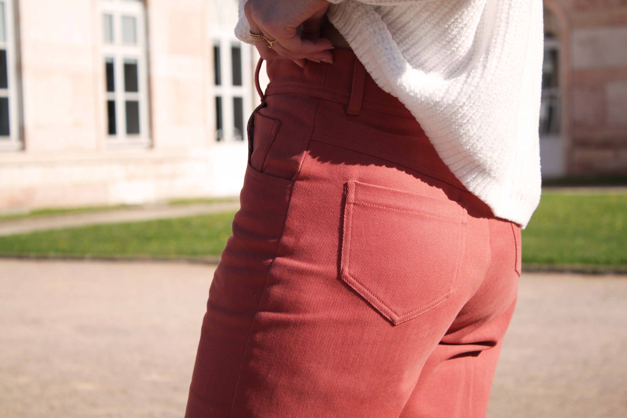 Close-up of the Jade Trousers back patch pockets and V-shaped yoke in rust-red fabric