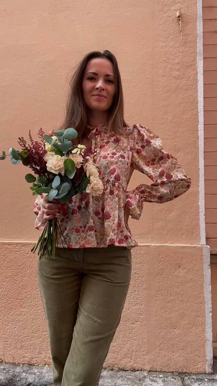 Full-length front view of the floral Alessia Blouse with olive trousers and a bouquet