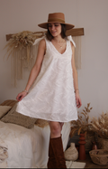 Jeanne Dress sewing pattern by Cha' coud sewn in white embroidered cotton with shoulder ties, worn with a hat and boots