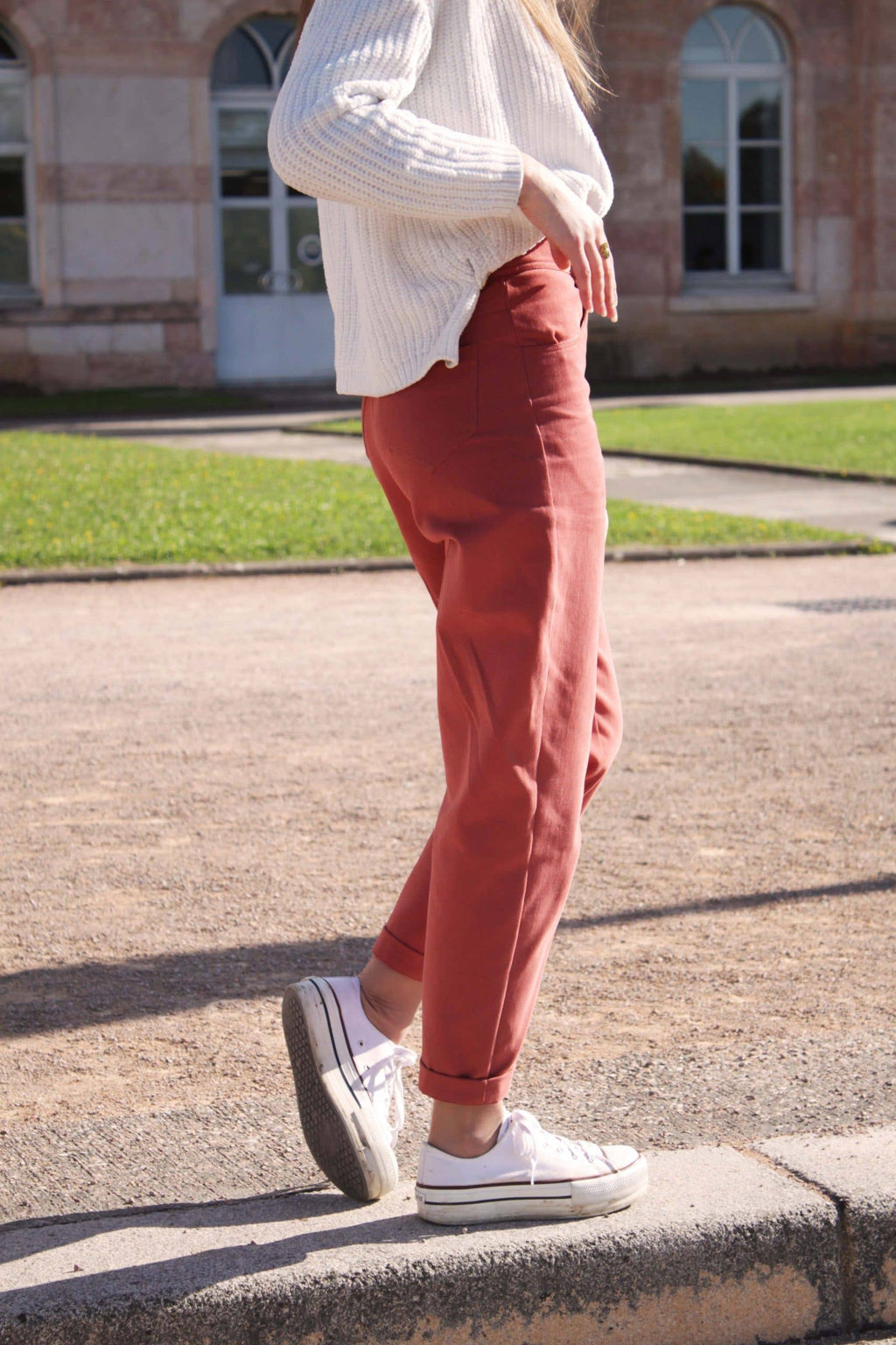 Side view of the rust-red straight-leg Jade Trousers with white sneakers