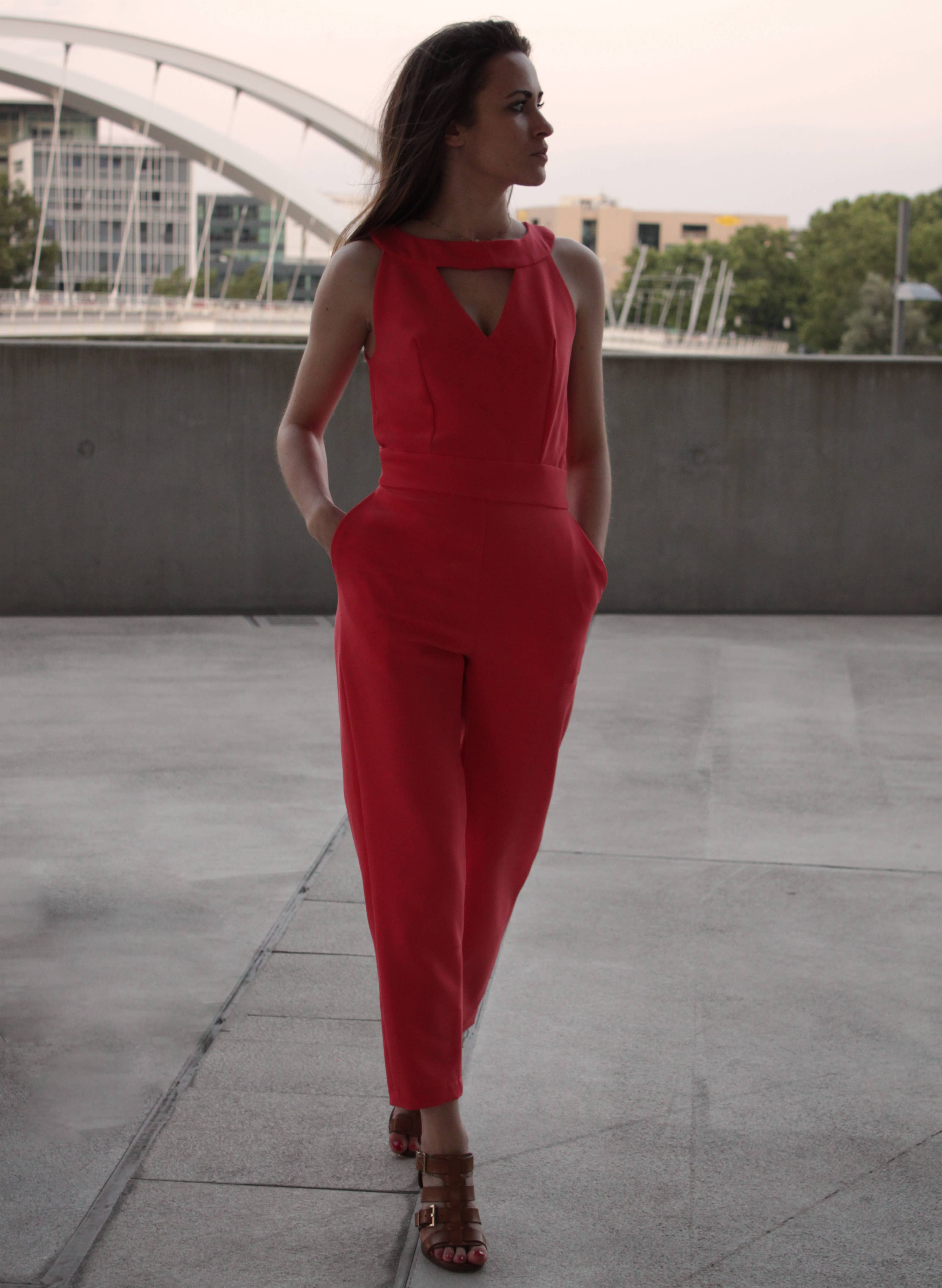 Red Aurore Jumpsuit with keyhole neckline and inseam pockets, front view on a terrace