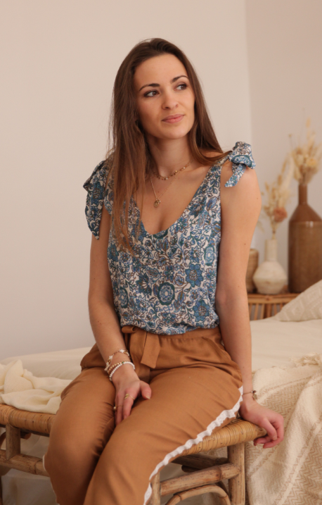Jeanne top version sewn in blue floral fabric, worn seated with camel trousers