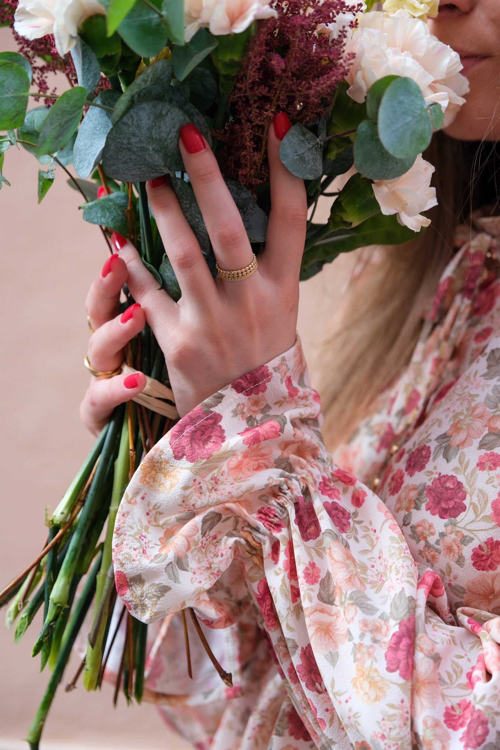 Close-up of the Alessia Blouse tie cuff in rose floral fabric, holding a bouquet