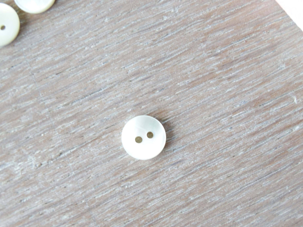 Close-up of Atelier 27 ivory pearlescent button showing natural nacre iridescence
